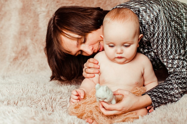 La mamma gioca con un bambino piccolo su un tappeto soffice