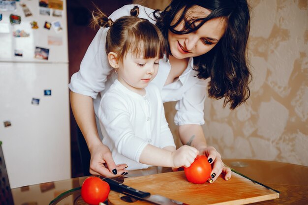 La mamma insieme a sua figlia cucina le verdure a casa in cucina