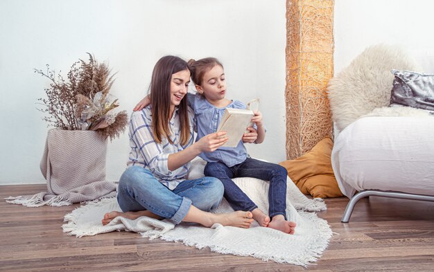 La mamma legge un libro con le sue figlie a casa.