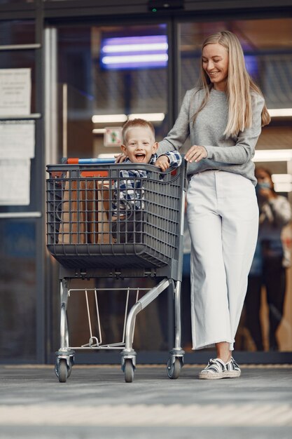 La mamma sta guidando in un carrello. Famiglia in un parcheggio vicino a un supermercato.