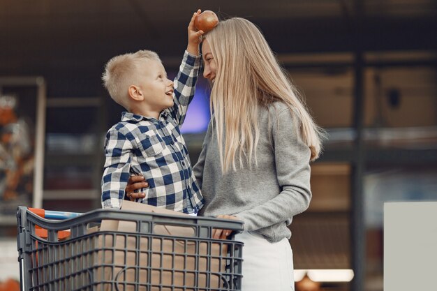 La mamma sta guidando in un carrello. Famiglia in un parcheggio vicino a un supermercato.