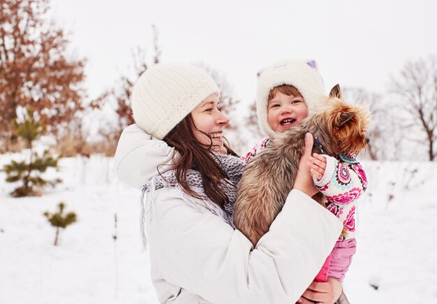 La mamma tiene la figlia sorridente e il cagnolino sulle mani