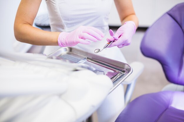 La mano del dentista che tiene specchio dentario in clinica