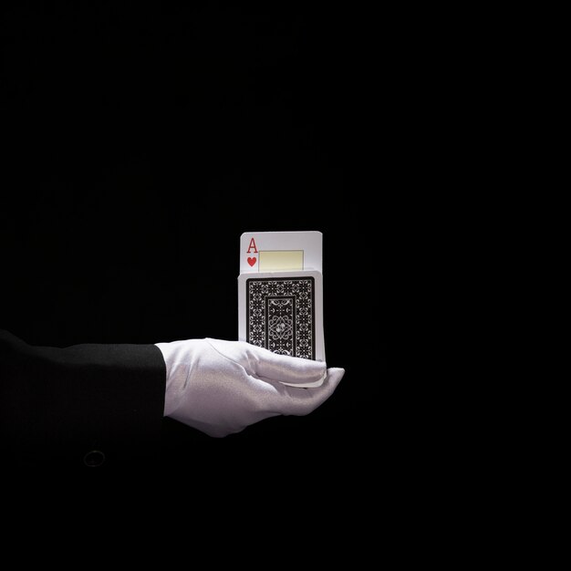 La mano del mago indossa guanti bianchi che eseguono il trucco su carte da gioco