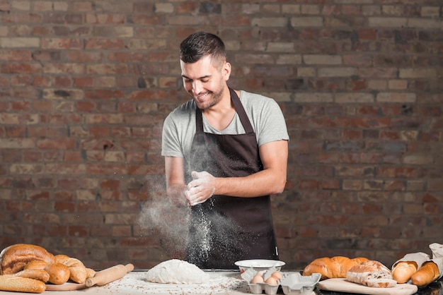 La mano del panettiere che applaude una farina con gli ingredienti sul contatore