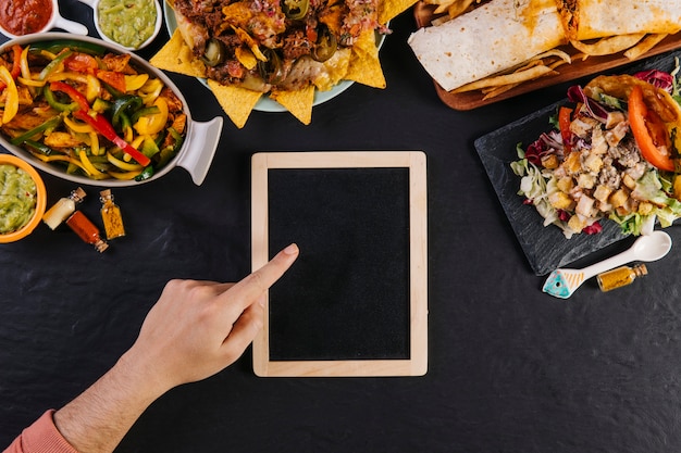 La mano del raccolto che indica alla lavagna vicino al cibo