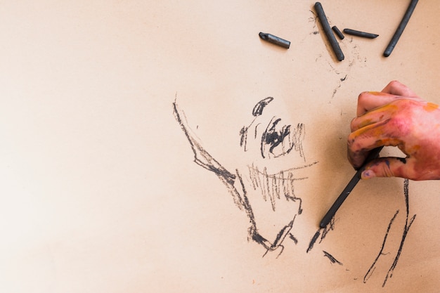 La mano dell&#39;artista che abbozza il disegno con carbone di legna su carta