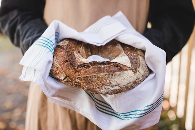 La mano della donna che mostra il pane rustico del bagel in tovagliolo bianco