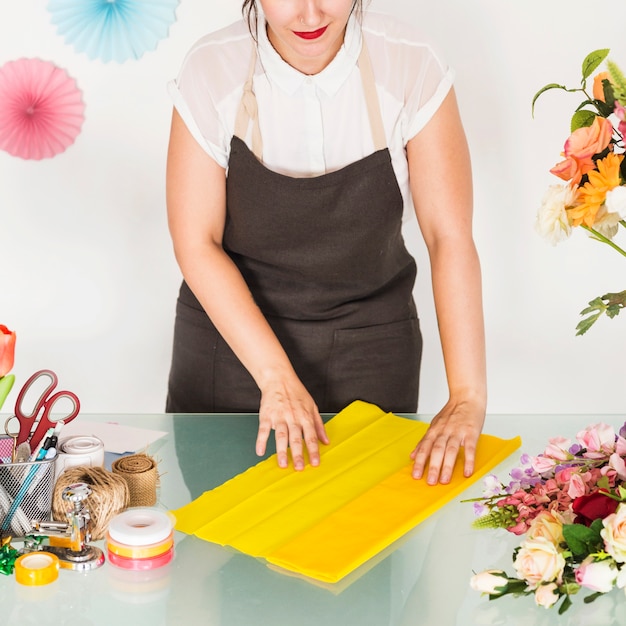 La mano della donna che organizza il panno giallo per fare bouquet di fiori sulla scrivania