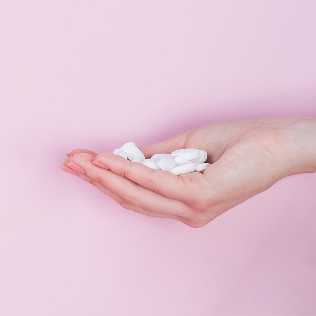 La mano della donna che tiene le pillole bianche della medicina farmaceutica