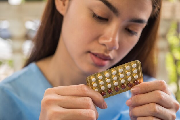 La mano della donna che tiene un pannello contraccettivo impedisce la gravidanza