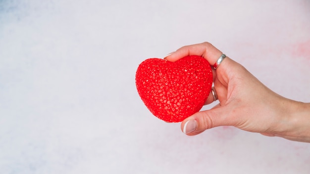 La mano della donna con cuore decorativo rosso