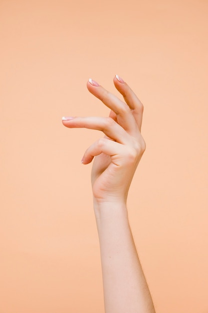 La mano della donna di Sideview su fondo arancio pallido