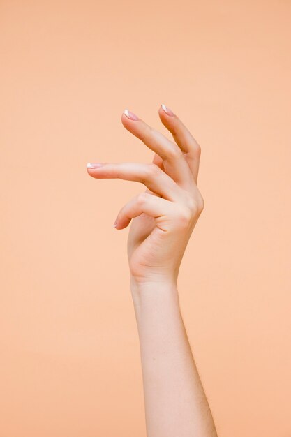 La mano della donna di Sideview su fondo arancio pallido