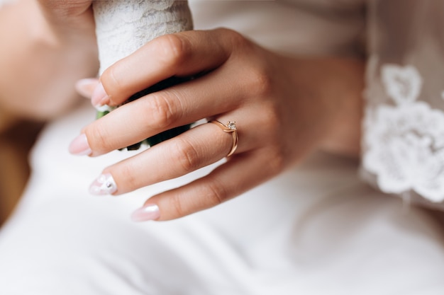 La mano della sposa con un anello di fidanzamento minimalista con un diamante