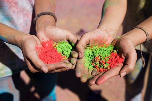 La mano delle donne che tiene i colori rossi e verdi di holi