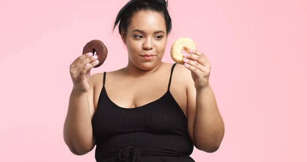 La modella plus size in studio spara sorridendo e mangia una ciambella