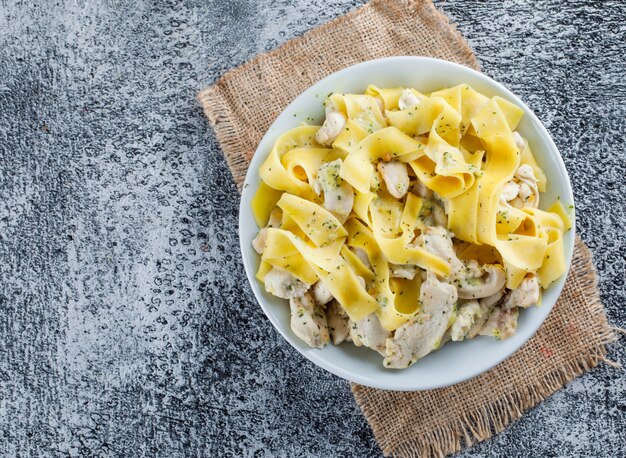 La pasta con carne in un piatto piatto giaceva su grungy e pezzo di sacco