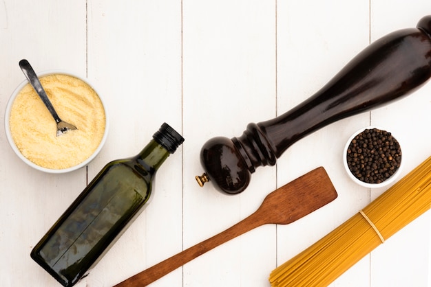 La pasta cruda degli spaghetti ed è ingrediente con l'utensile della cucina sulla tavola bianca