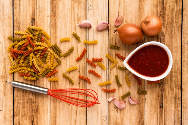 La pasta e l'ingrediente crudi con sbattono sulla tavola di legno