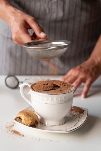 La persona versa il cacao in polvere in tazza