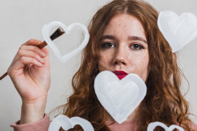 La pittura della giovane donna riscalda e guardando il fotografo