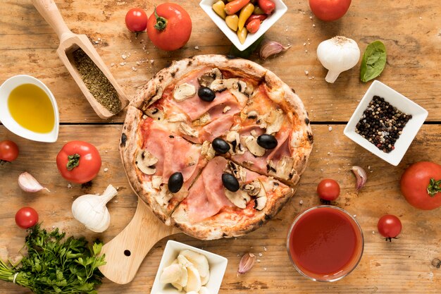 La pizza appena sfornata è circondata da ingredienti sopra una scrivania strutturata