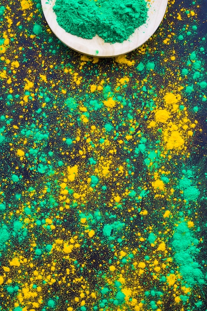La polvere verde e gialla di holi schizza su fondo nero