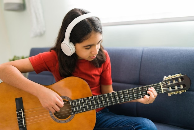 La pratica rende perfetti. Bella ragazza ispanica che memorizza e si esercita con gli accordi di chitarra nel suo strumento acustico