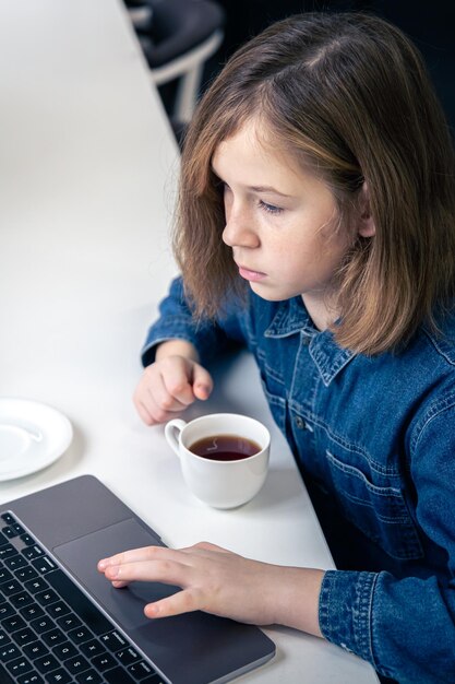 La ragazza adolescente si siede di fronte a un computer portatile per l'apprendimento online