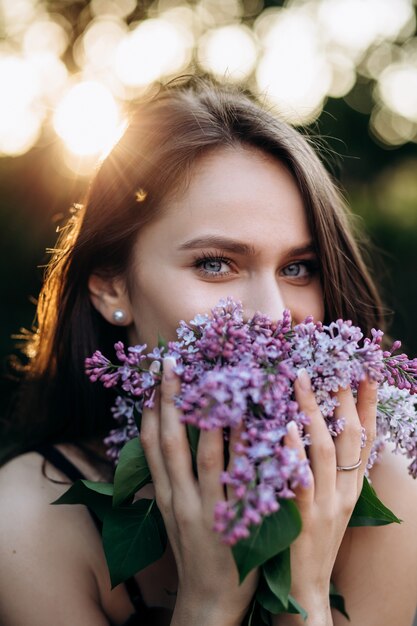 La ragazza affascinante si trova nel parco e mantiene un bouquet