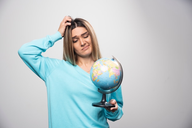 La ragazza bionda in felpa blu tiene un globo e sembra incerta e confusa