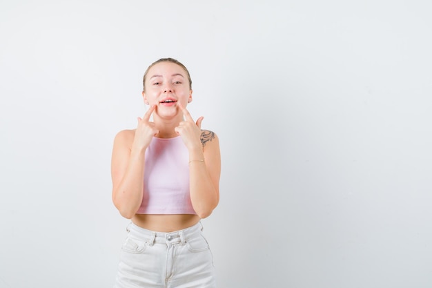 La ragazza bionda sta facendo sorridere con le sue dita su priorità bassa bianca