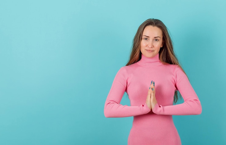 Foto gratuito la ragazza bionda sta tenendo le mani insieme nella preghiera su sfondo blu