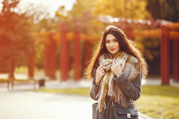 La ragazza cammina. Donna in un cappotto. Bruna con una sciarpa.