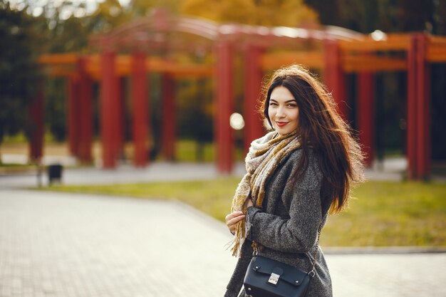 La ragazza cammina. Donna in un cappotto. Bruna con una sciarpa.