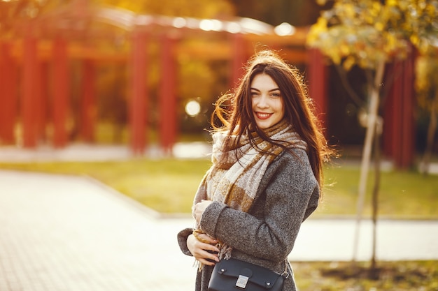 La ragazza cammina. Donna in un cappotto. Bruna con una sciarpa.