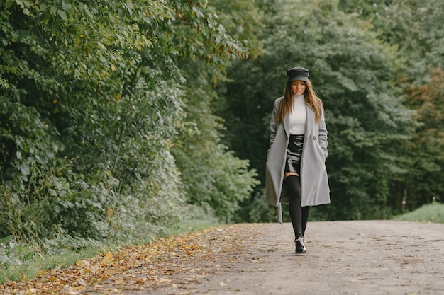 La ragazza cammina. Donna in un cappotto grigio. Bruna con un berretto nero.