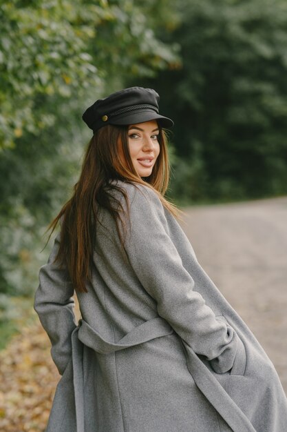 La ragazza cammina. Donna in un cappotto grigio. Bruna con un berretto nero.