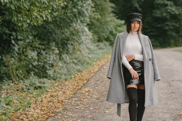 La ragazza cammina. Donna in un cappotto grigio. Bruna con un berretto nero.