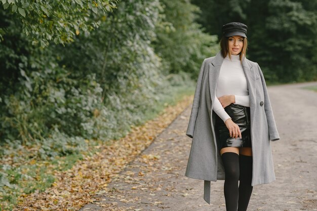 La ragazza cammina. Donna in un cappotto grigio. Bruna con un berretto nero.