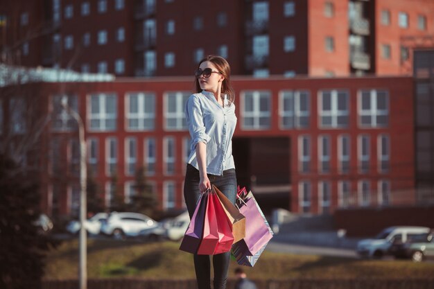 La ragazza che cammina con lo shopping per le strade della città