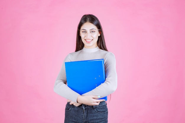 La ragazza che tiene una cartella di progetto blu e sembra riuscita e felice