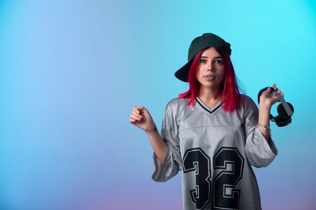 La ragazza con i capelli rosa sembra positiva e tiene le cuffie.