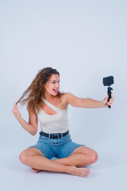 La ragazza con il mimetismo divertente sta prendendo selfie con la sua mini macchina fotografica tenendo i capelli