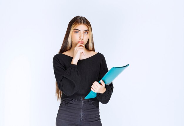 La ragazza con una cartella blu sembra confusa e pensierosa. Foto di alta qualità