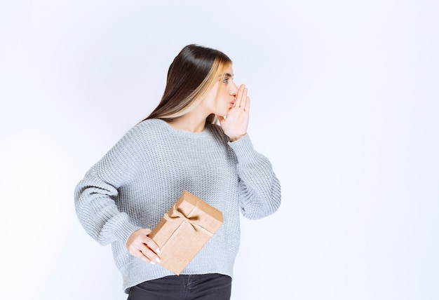 La ragazza con una confezione regalo di cartone sembra confusa ed elettrizzata.