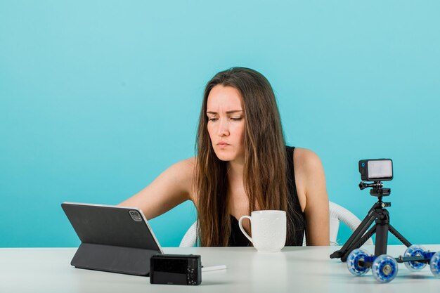 La ragazza del blogger sta guardando lo schermo del tablet su sfondo blu