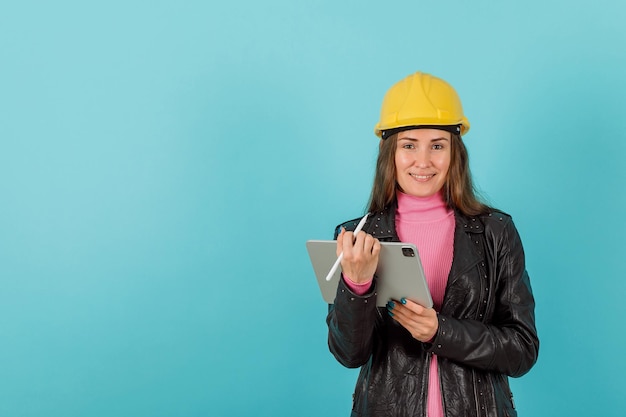 La ragazza dell'architetto con il planshet della compressa sta sorridendo su fondo blu