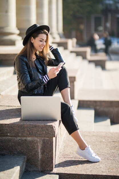 La ragazza dello studente della giovane donna di affari lavora con il suo computer portatile di marca nel centro urbano